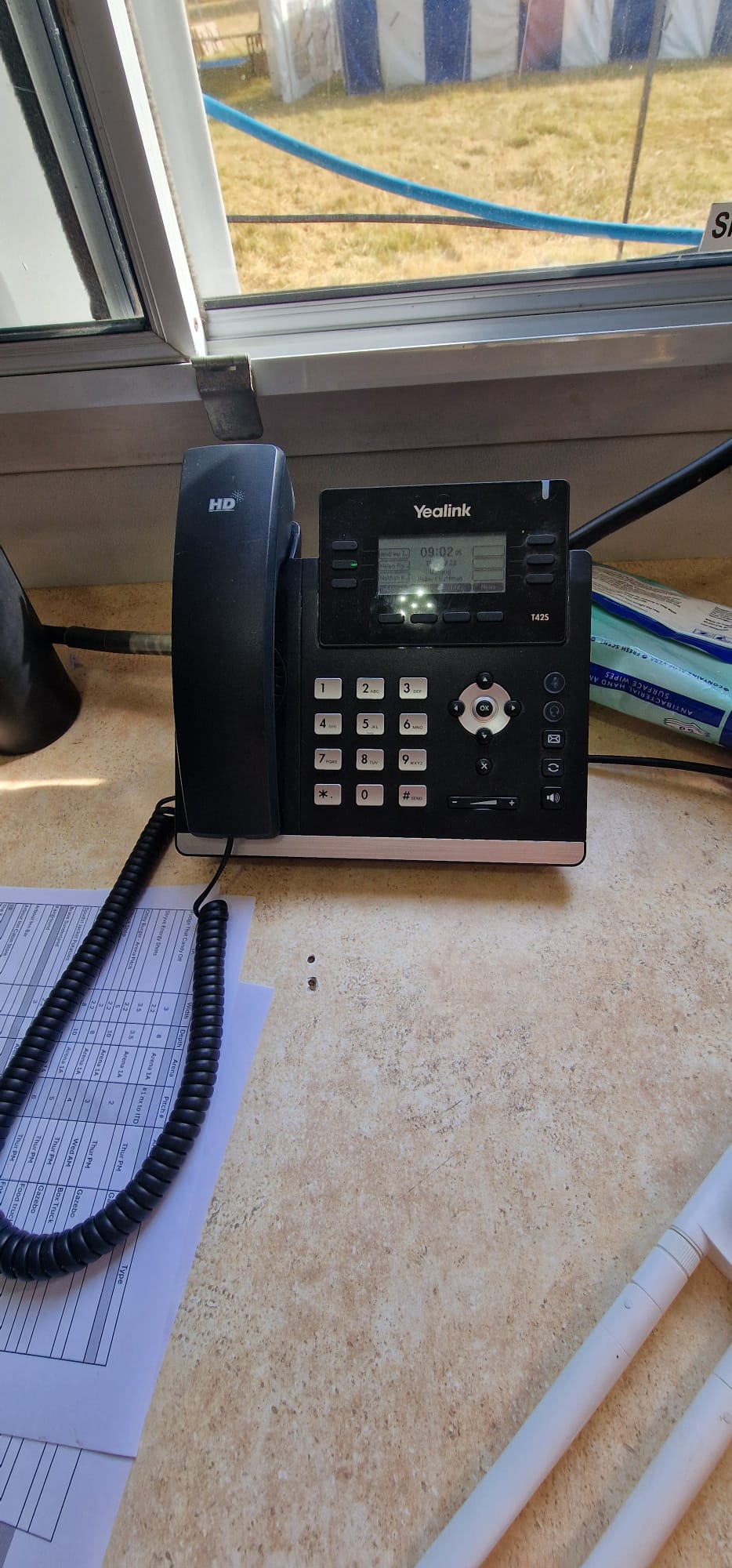 VoIP desk phone operational at Deershed Festival 2026 with festival site visible through the window